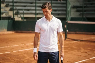 Joueur de tennis concentré effectuant un rituel mental entre les points sur un court en terre battue lors d'un tournoi