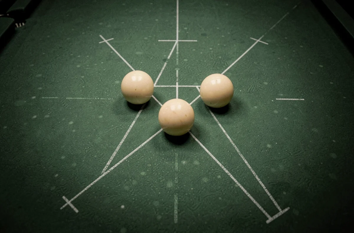 Vue aérienne d'une table de billard trois bandes avec des billes positionnées et des repères de trajectoire tracés sur le tapis vert, symbolisant le calcul des angles de rotation